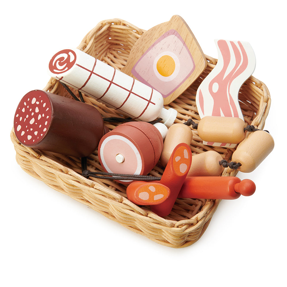 A hand crafted wicker basket with continental charcuterie set that is part of the market stall range. This set includes a slice of ham and egg pie, a black sausage, a rasher of bacon,  a string of butchers sausages, a large salami, a spanish corizo style sausage, and a ham hock.