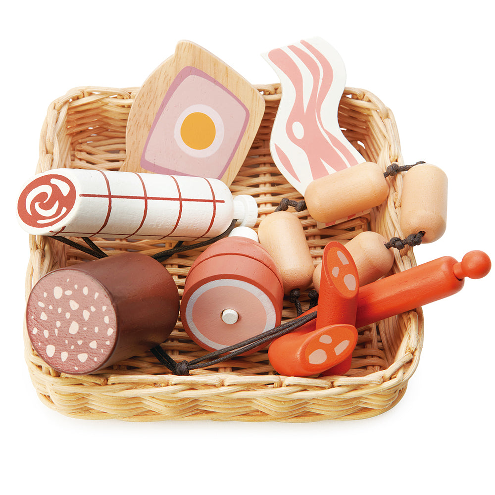 A hand crafted wicker basket with continental charcuterie set that is part of the market stall range. This set includes a slice of ham and egg pie, a black sausage, a rasher of bacon,  a string of butchers sausages, a large salami, a spanish corizo style sausage, and a ham hock.